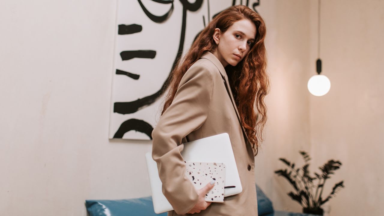 Woman in Brown Coat Holding Laptop Computer